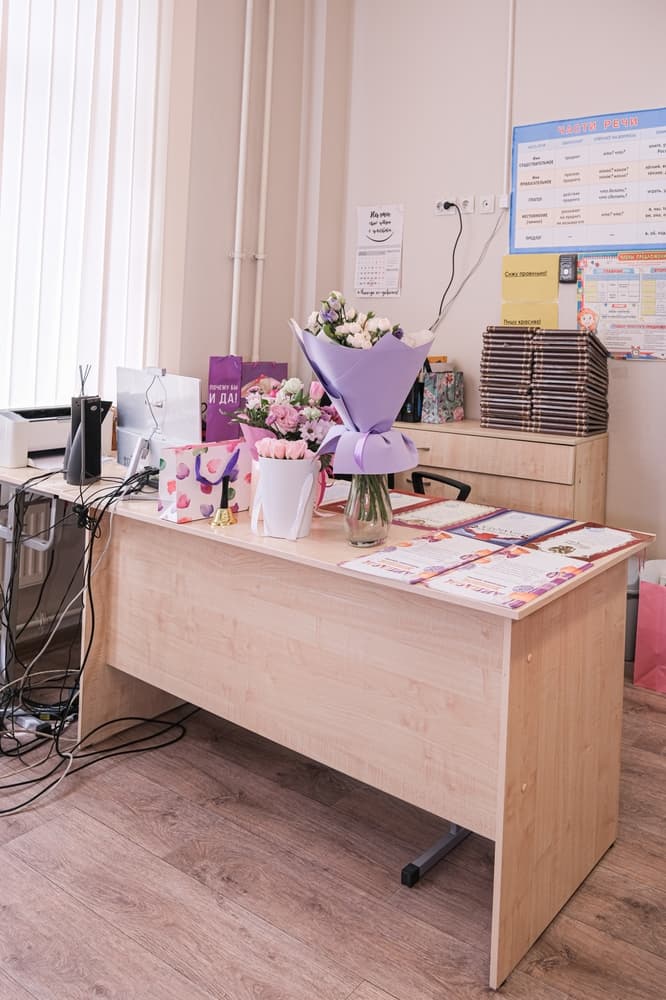 Mesa de una profesora con regalos y flores